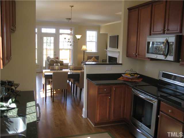 1532 Yarborough Park Drive Raleigh, NC 27604 - Photo 5 of 10 a kitchen with stainless steel appliances granite countertop a stove top oven a dining table and chairs with wooden floor