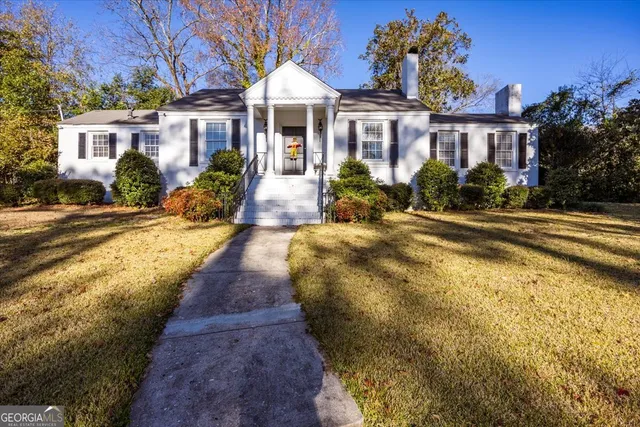 a view of a white house with a swimming pool and lawn chairs with wooden fence
