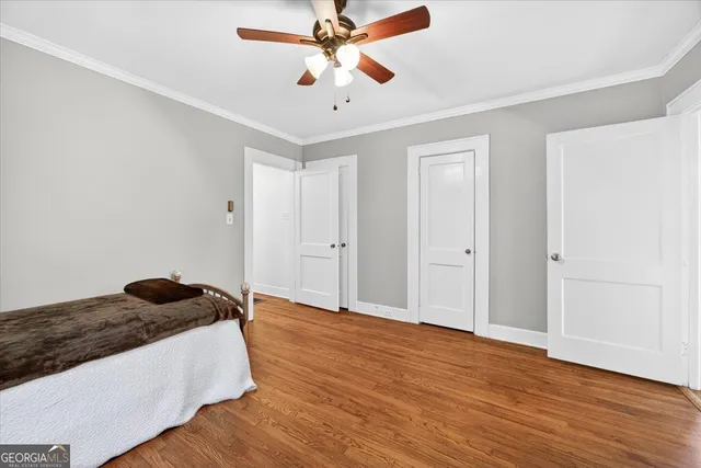 a bedroom with wooden floor a ceiling fan and closet