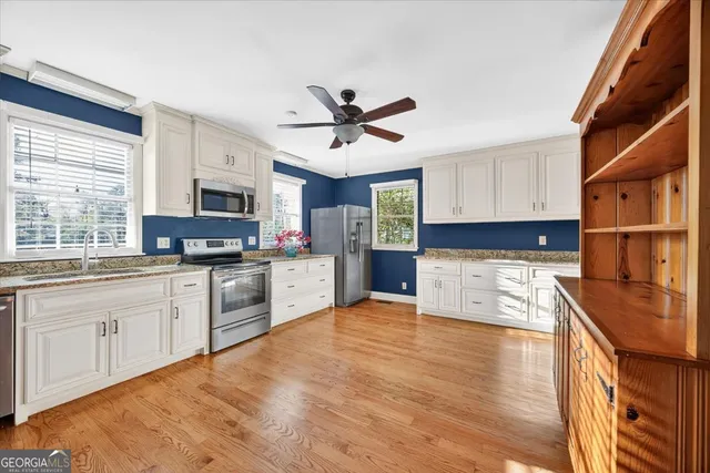 a kitchen with stainless steel appliances granite countertop a sink cabinets and wooden floor