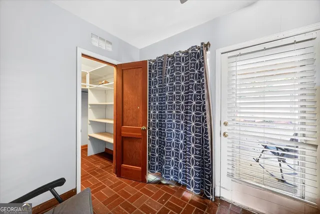 an empty room with wooden floor chandelier and windows
