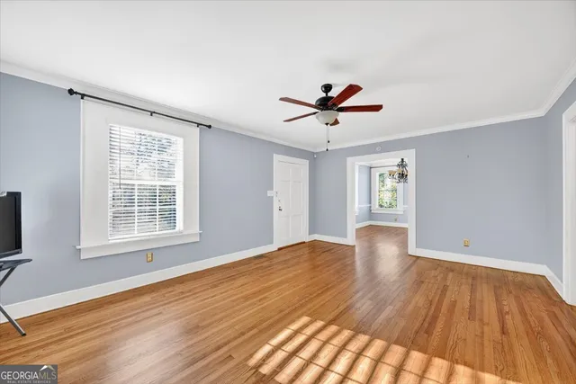 a view of an empty room with a window and wooden floor