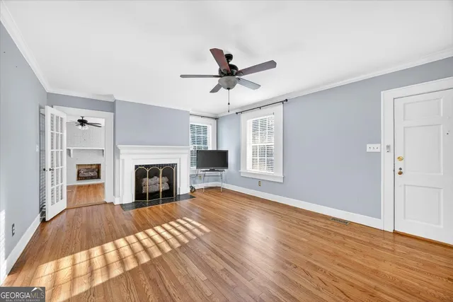 a view of a livingroom with a fireplace a ceiling fan and brick wall clock