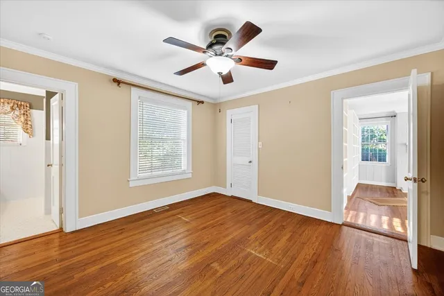 a view of empty room with wooden floor and fan