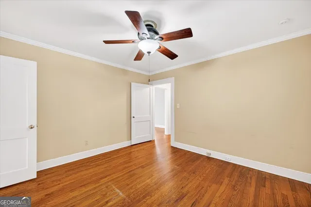 an empty room with wooden floor ceiling fan and window