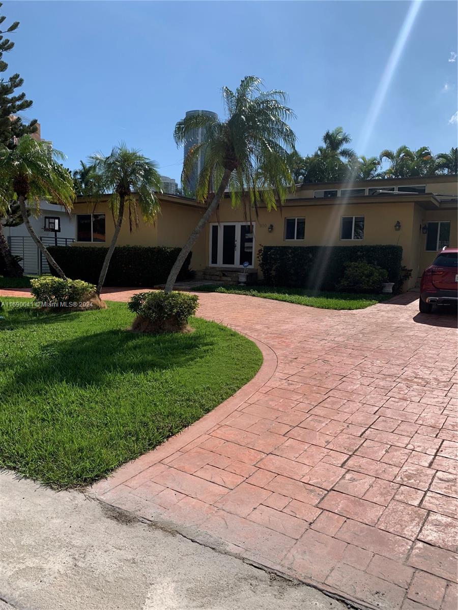 310 191st Terrace Sunny Isles Beach, FL 33160 - Photo 2 of 36 a front view of a house with a yard and potted plants