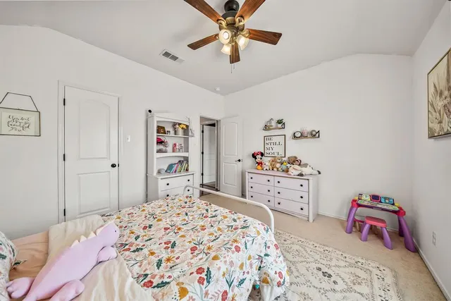 a bedroom with a bed a dresser and paintings