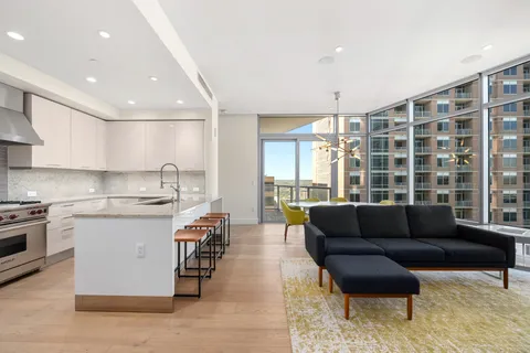 a kitchen with stainless steel appliances granite countertop a stove and a view of living room