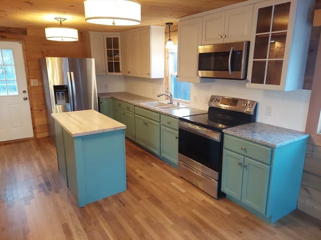 a large kitchen with stainless steel appliances granite countertop a lot of counter space and wooden floor