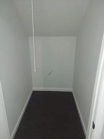 an empty room with wooden floor cabinets and entrance