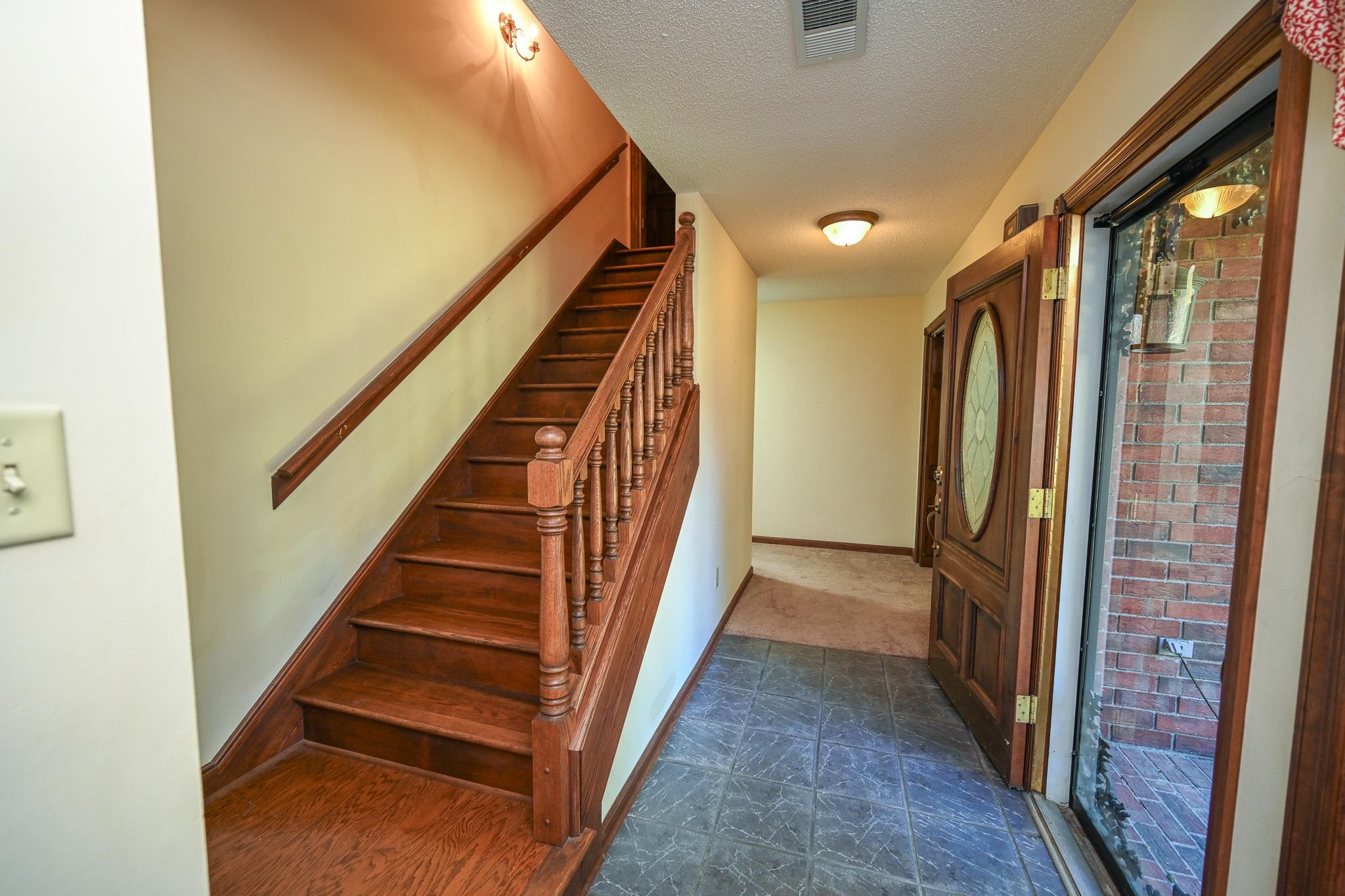 3746 Broadway Road Bartlett, TN 38135 - Photo 7 of 39 Entryway featuring a wood-finish staircase with baluster railing, tile flooring, and a decorative wood-panel front door with an oval glass insert.