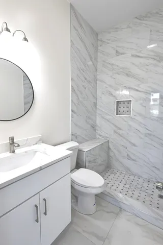 a bathroom with a granite countertop toilet sink mirror and vanity
