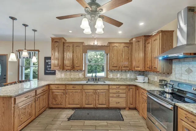 a large kitchen with stainless steel appliances granite countertop a stove a sink and a refrigerator