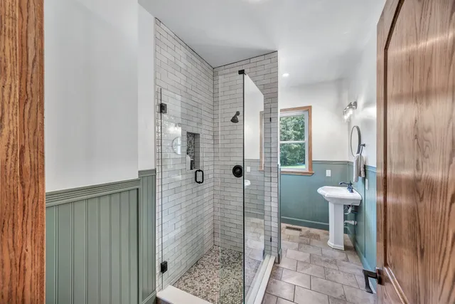 a bathroom with a glass shower door and a mirror