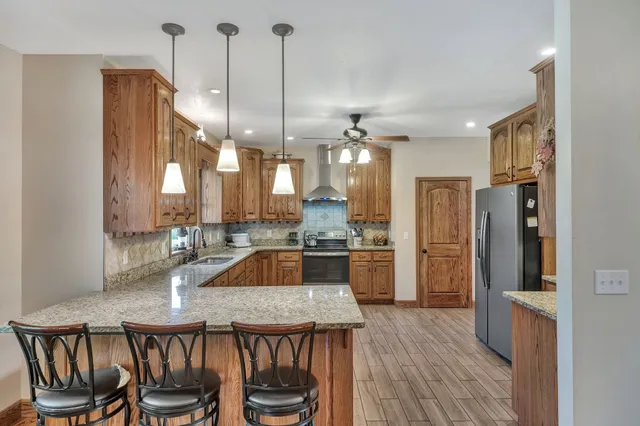 a kitchen with stainless steel appliances granite countertop a refrigerator a stove and a wooden floor