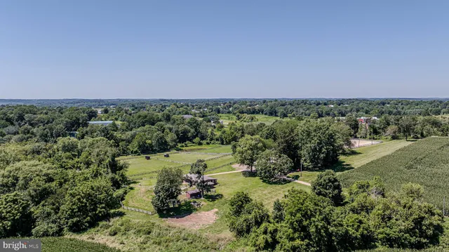 an aerial view of a residential houses with outdoor space and trees all around