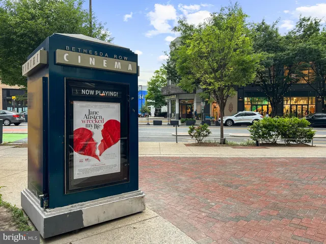 a front view of a building with lots of flowers and trees