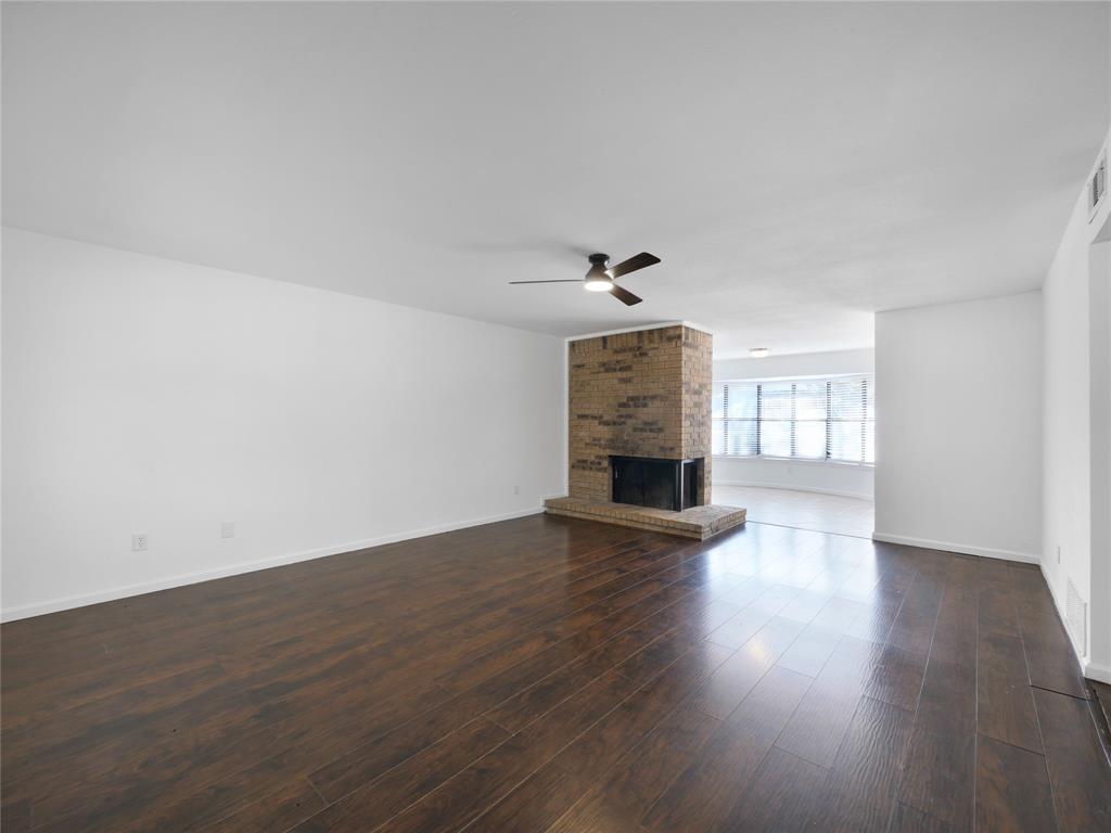 1472 Rockshire Drive Plano, TX 75074 - Photo 5 of 27 Expansive room featuring wood-finish flooring, a brick fireplace with hearth, and a ceiling fan