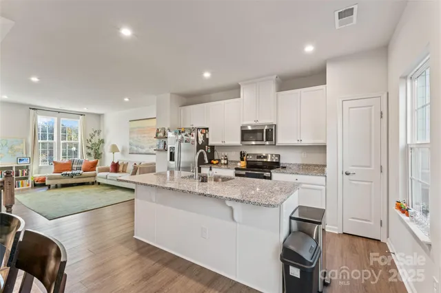 a kitchen with stainless steel appliances a sink a stove a refrigerator cabinets and living room