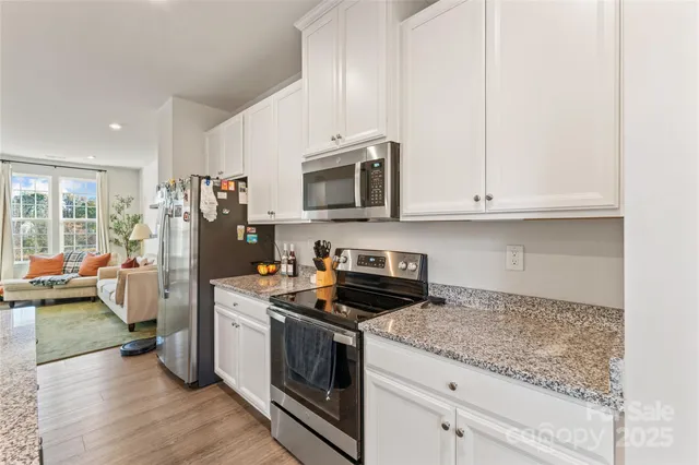 a kitchen with stainless steel appliances granite countertop a stove a refrigerator and a white cabinets