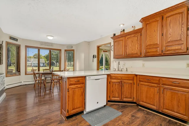 a kitchen with stainless steel appliances granite countertop a refrigerator a stove a sink and white cabinets with wooden floor