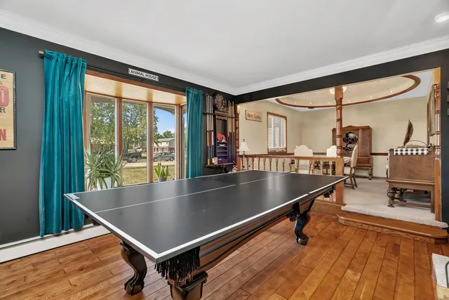 a room with wooden floor pool table and windows
