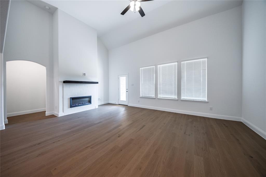 102 National Court Forney, TX 75126 - Photo 6 of 26 an empty room with wooden floor a fireplace and windows