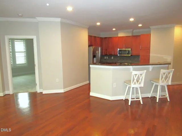 a view of a dining room with kitchen island stainless steel appliances wooden floor and view living room