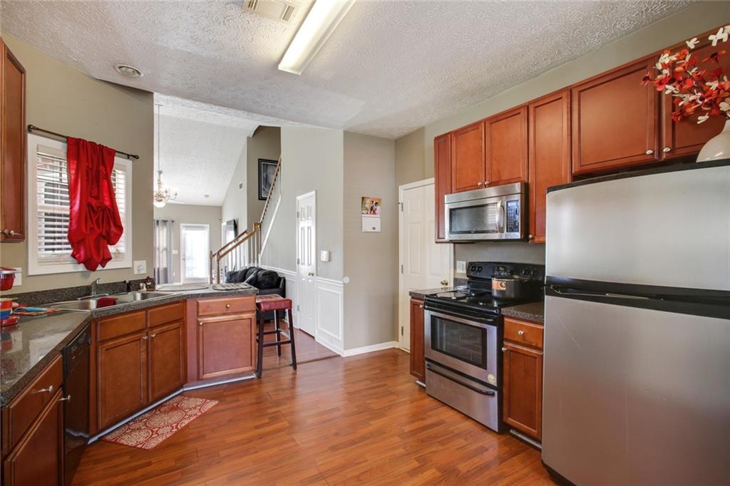 2555 Flat Shoals Road, Unit 1801 Atlanta, GA 30349 - Photo 11 of 24 a kitchen with stainless steel appliances a sink cabinets and a wooden floor