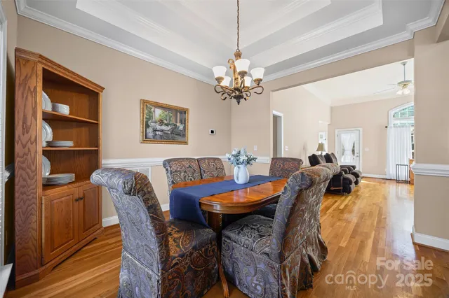 a view of a dining room and livingroom with furniture wooden floor a chandelier