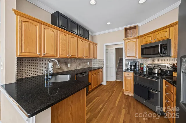 a kitchen with stainless steel appliances granite countertop a sink a stove top oven a chimney cabinets and a counter top space