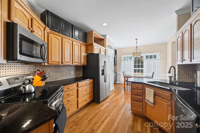 a kitchen with stainless steel appliances granite countertop a stove a sink dishwasher a refrigerator and cabinets with wooden floor