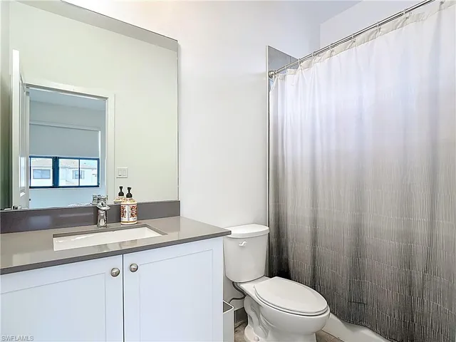 a bathroom with a sink a toilet a mirror and shower curtain