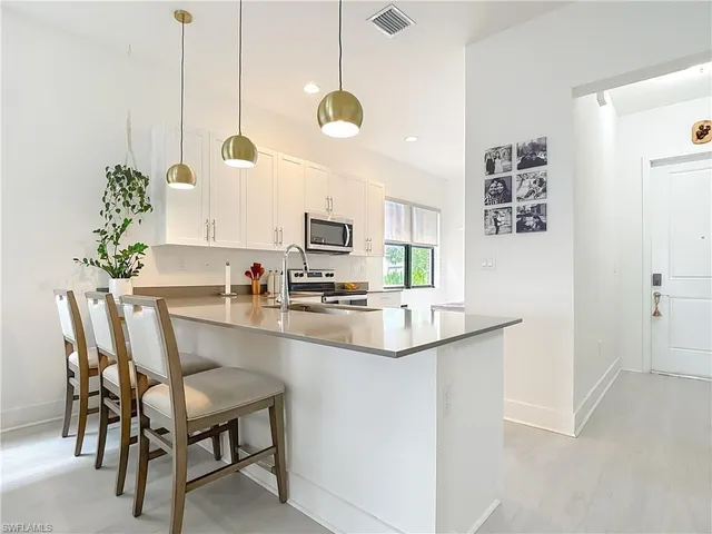 a kitchen with kitchen island a dining table chairs sink and cabinets