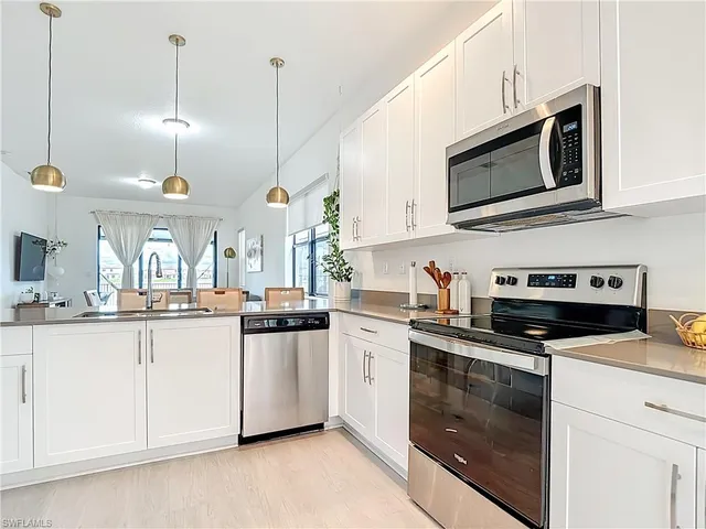 a kitchen with stainless steel appliances granite countertop a sink a stove a microwave and wooden cabinets