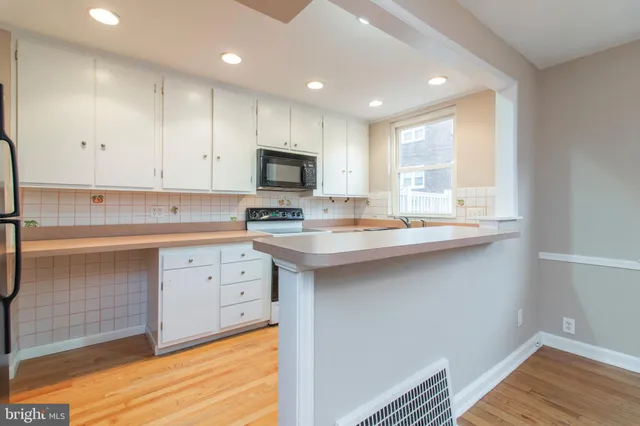 a kitchen with kitchen island granite countertop a sink cabinets and wooden floor