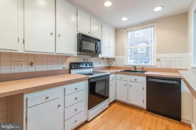 a kitchen with granite countertop white cabinets stainless steel appliances a sink and a window