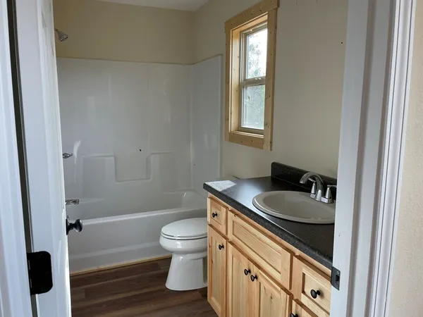 a bathroom with a granite countertop sink a toilet a mirror and shower