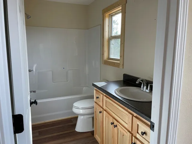 a bathroom with a granite countertop sink a toilet a mirror and shower