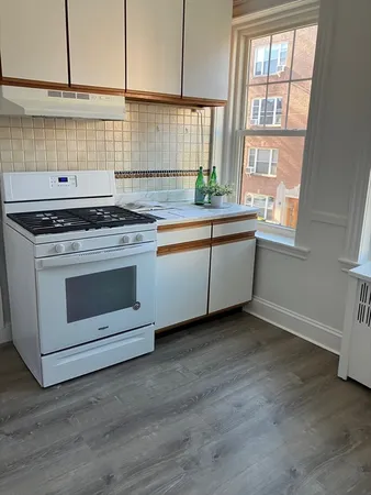 a kitchen with granite countertop white cabinets and a stove top oven