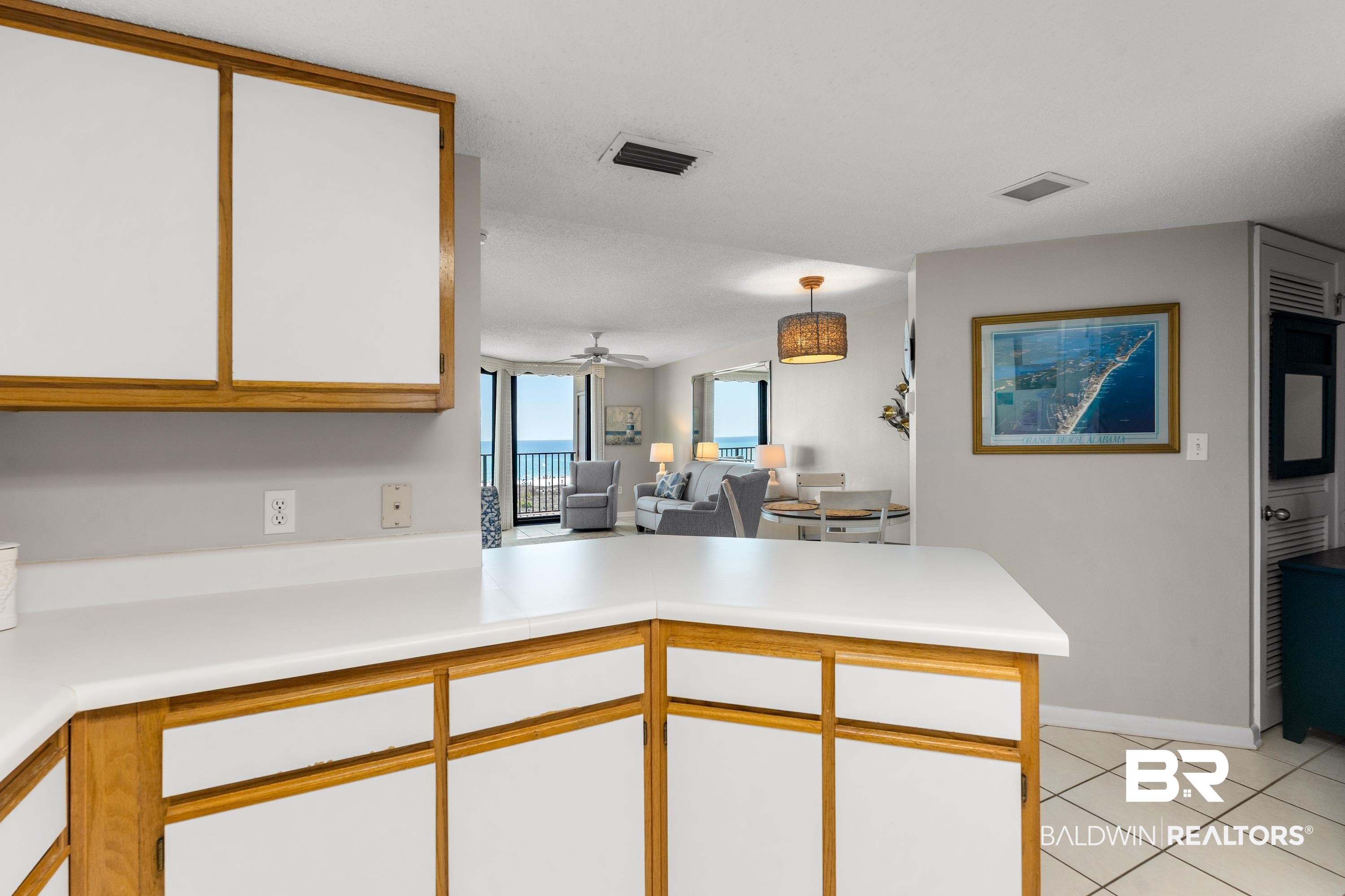 26802 Perdido Beach Boulevard, Unit 406 Orange Beach, AL 36561 - Photo 37 of 37 Dual tone kitchen featuring two tone cabinetry, a peninsula, light countertops, open floor plan, and decorative light fixtures