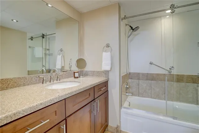 a bathroom with a granite countertop sink mirror and a bathtub