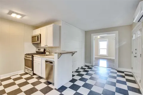 a kitchen with a checkered floor and white cabinets