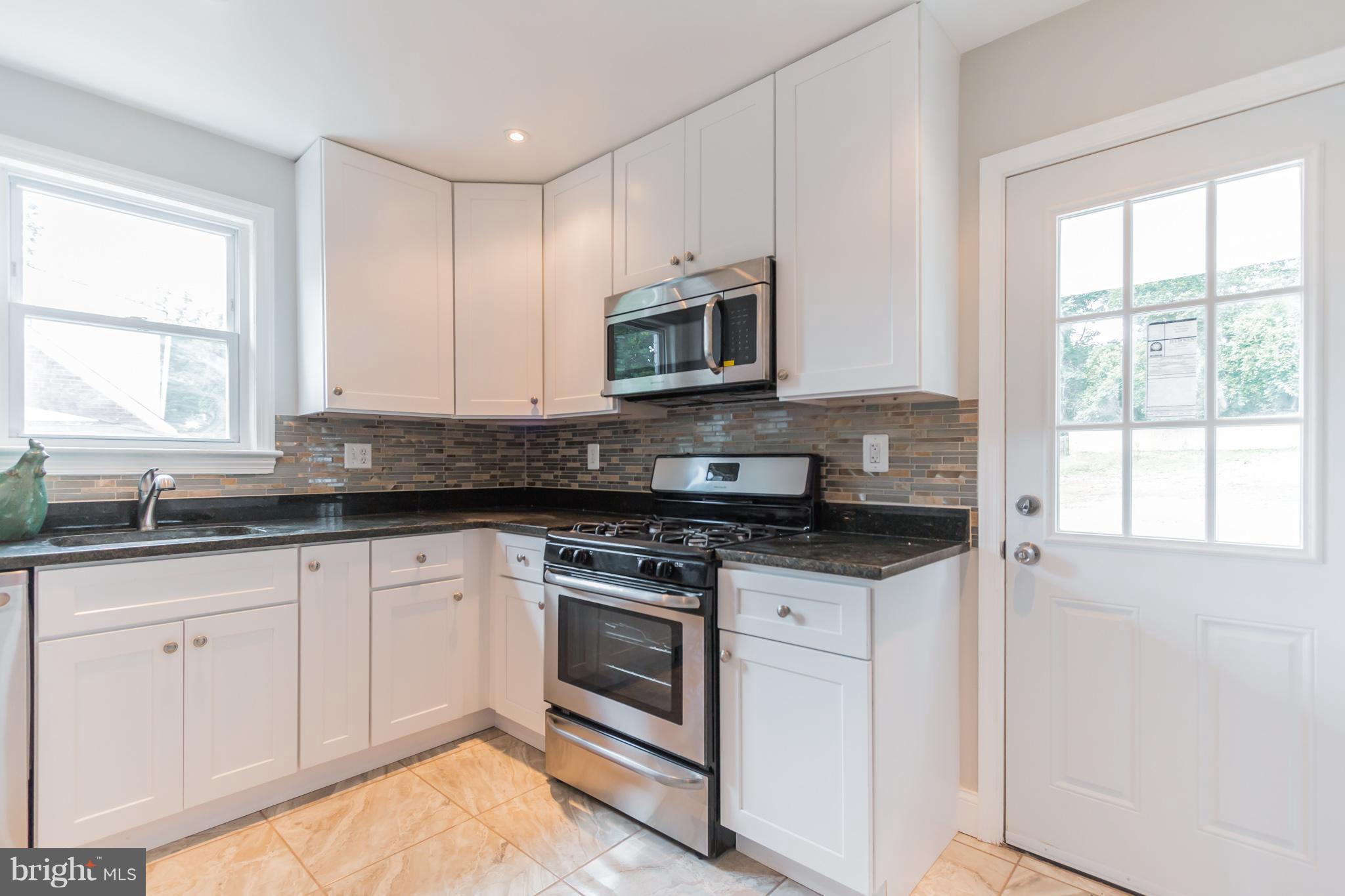 11508 Veirs Mill Road Silver Spring, MD 20902 - Photo 12 of 30 a kitchen with granite countertop white cabinets appliances a sink and a window