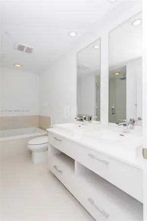 a bathroom with a double vanity sink toilet and a bathtub