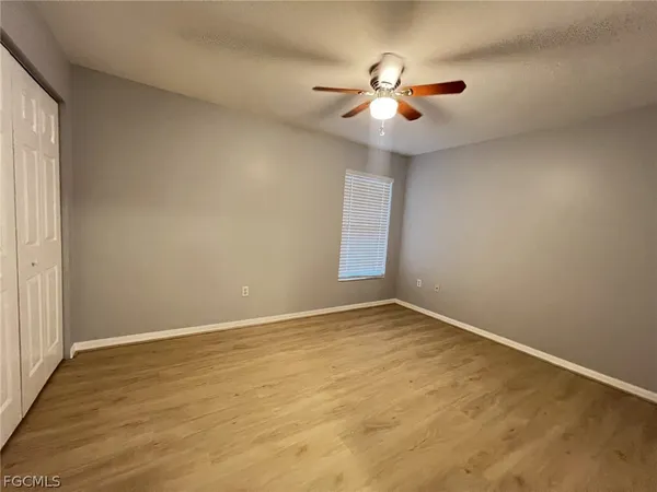 a view of an empty room with chandelier fan and fire place