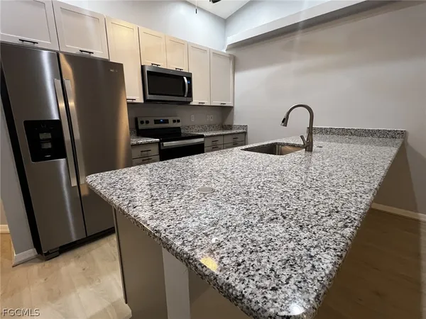 a kitchen with granite countertop a refrigerator and a stove top oven