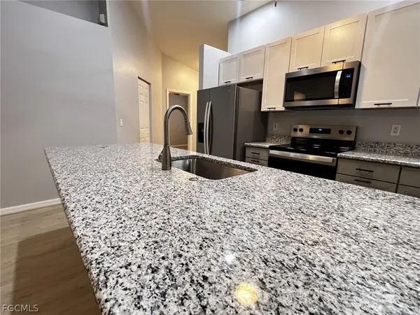a kitchen with stainless steel appliances kitchen island granite countertop a refrigerator and a sink