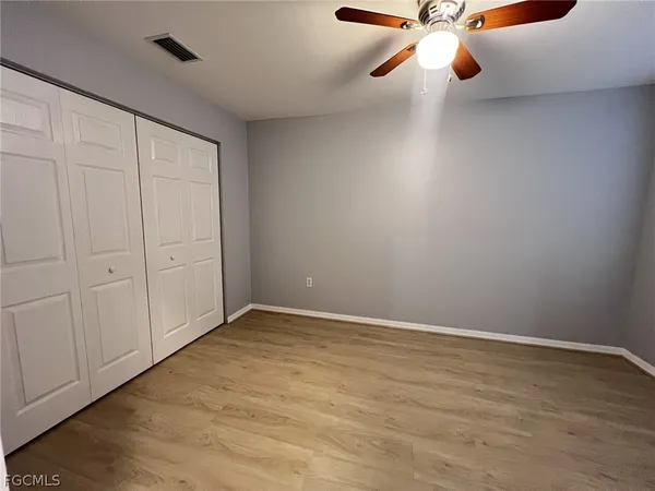 wooden floor in an empty room with a chandelier fan