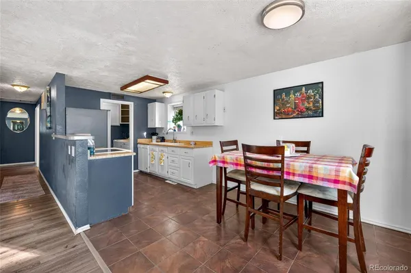 a living room with stainless steel appliances furniture a rug and a kitchen view